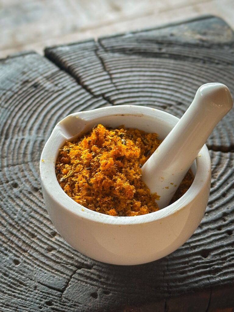 Coarsely ground sea buckthorn meal in a mortar.