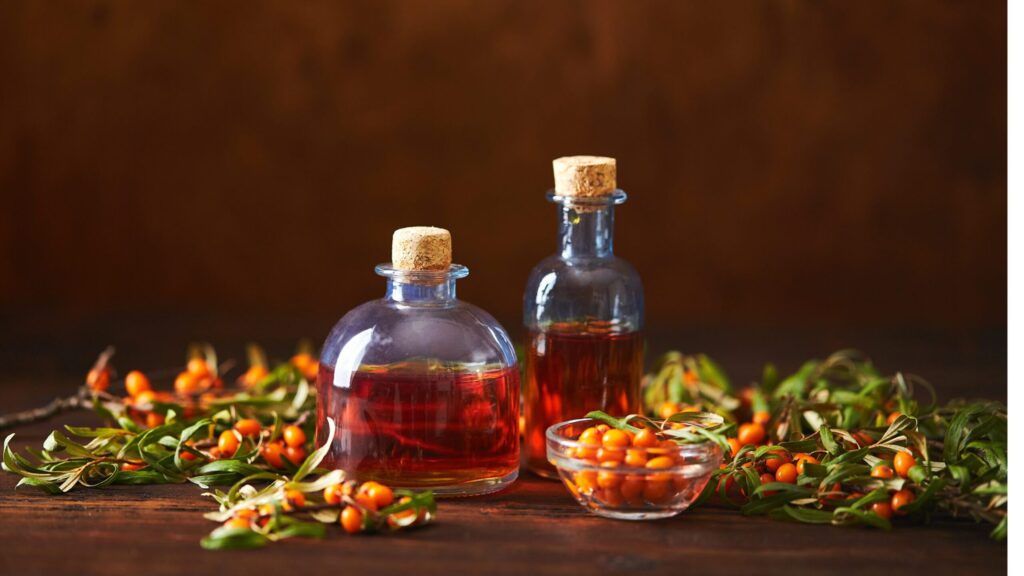 Carotenoid-rich sea buckthorn pulp oil with a naturally deep red-orange colour, shown in glass bottles alongside fresh sea buckthorn berries.