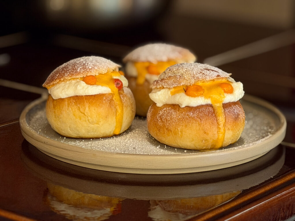 Nordic semla filled with white chocolate cream and sea buckthorn sauce on a plate